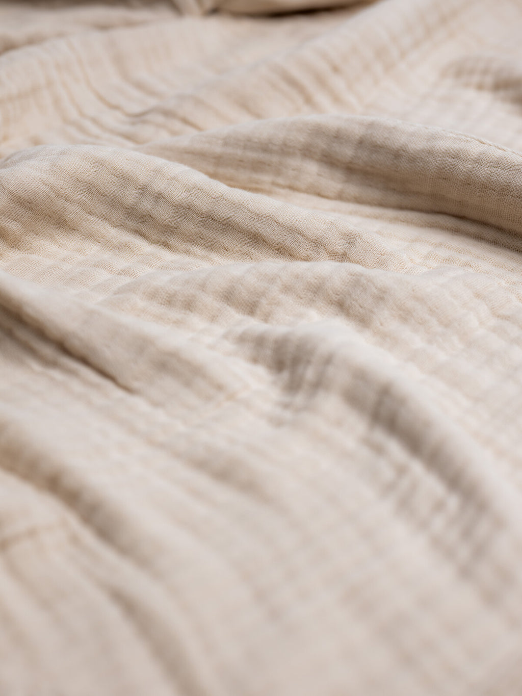 Makro posnetek bogate teksture 8-slojnega bombažnega muslina znamke Lefluf v bež barvi, ki prikazuje značilen naravno zmečkan videz in izjemno zračnost gostega tkanja.